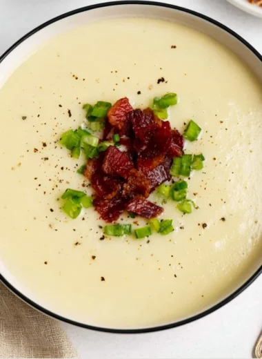 A cozy bowl of loaded potato soup topped with cheese and chives.