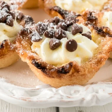 Delicious creamy mini cannoli cups topped with chocolate and powdered sugar