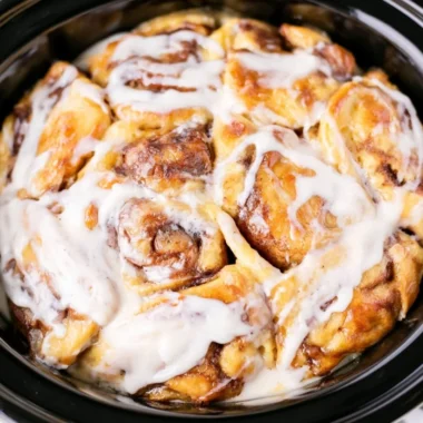 Crockpot cinnamon roll casserole fresh out of the slow cooker, topped with icing.