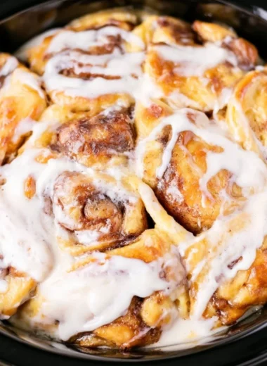 Crockpot cinnamon roll casserole fresh out of the slow cooker, topped with icing.