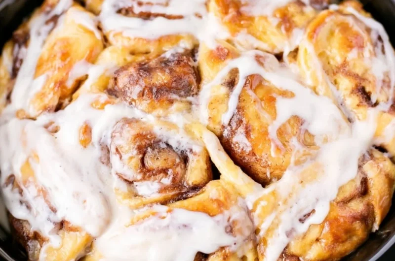 Crockpot cinnamon roll casserole fresh out of the slow cooker, topped with icing.