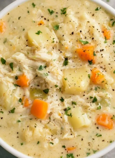 High protein chicken pot pie soup topped with herbs in a bowl.