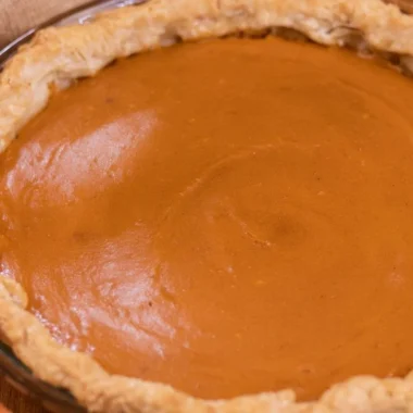 A slice of my favorite sweet potato pie topped with whipped cream on a plate.