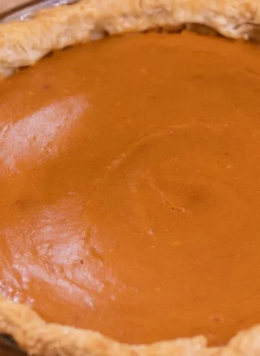 A slice of my favorite sweet potato pie topped with whipped cream on a plate.