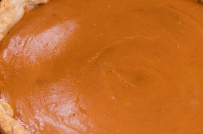 A slice of my favorite sweet potato pie topped with whipped cream on a plate.