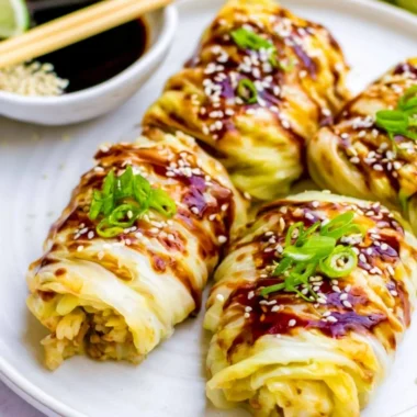 Delicious stuffed cabbage rolls served on a plate with herbs and sauce.