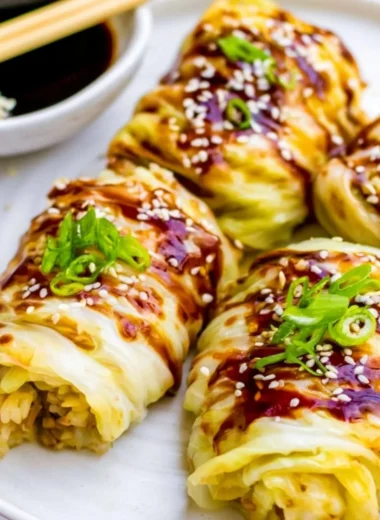 Delicious stuffed cabbage rolls served on a plate with herbs and sauce.