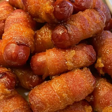 Bacon wrapped little smokies served on a platter with dipping sauce.