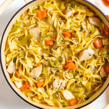 Delicious Dutch Oven Chicken Noodle Soup in a bowl, garnished with fresh herbs.