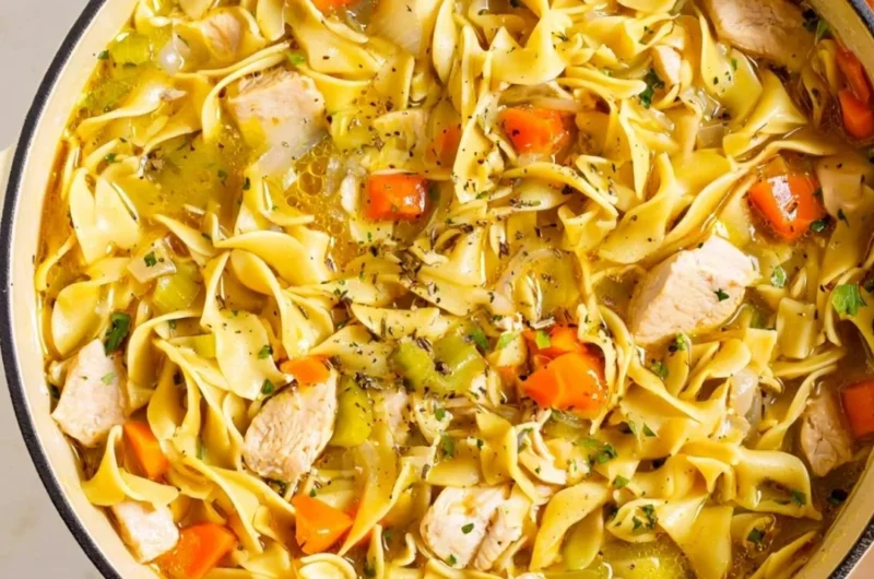 Delicious Dutch Oven Chicken Noodle Soup in a bowl, garnished with fresh herbs.
