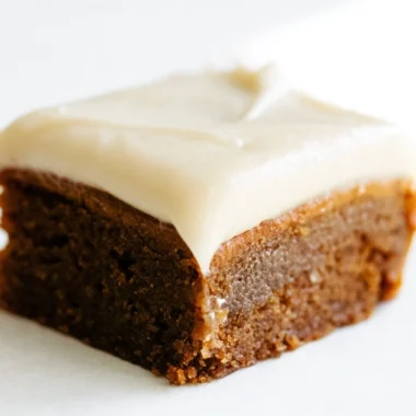 Gingerbread cookie bars with cream cheese frosting on a festive plate.