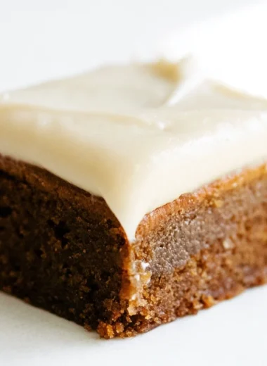 Gingerbread cookie bars with cream cheese frosting on a festive plate.