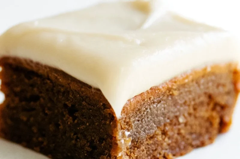 Gingerbread cookie bars with cream cheese frosting on a festive plate.
