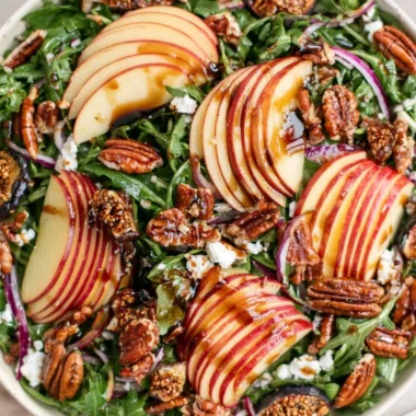 Fresh apple arugula salad with slices of apple and dressing in a bowl