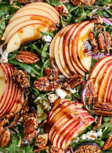 Fresh apple arugula salad with slices of apple and dressing in a bowl