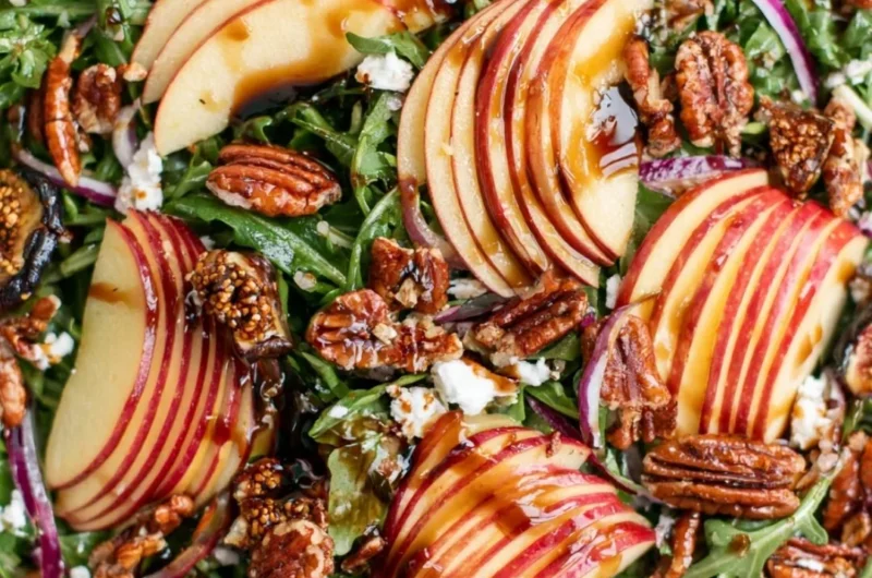 Fresh apple arugula salad with slices of apple and dressing in a bowl